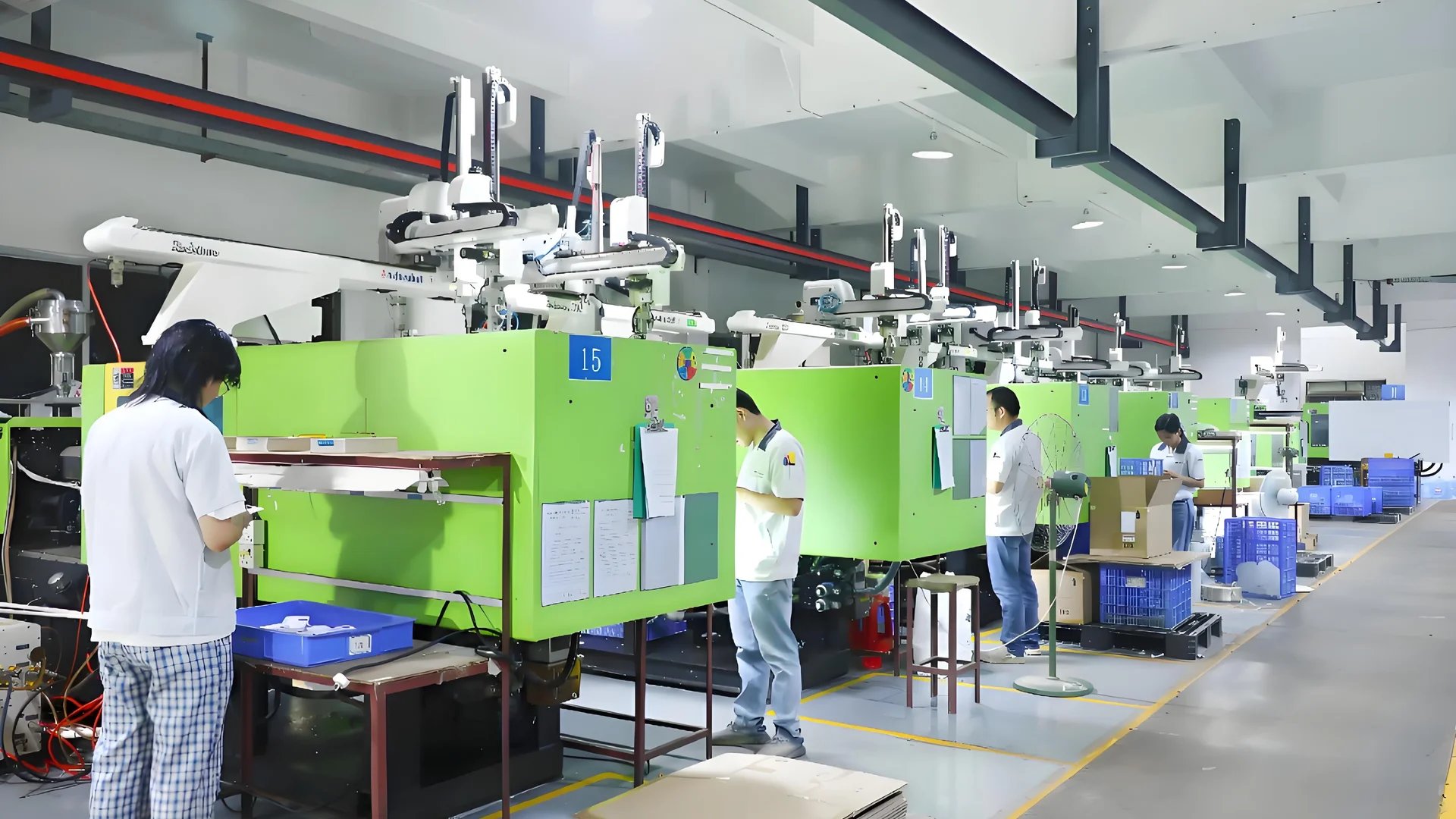 A busy industrial manufacturing facility with green injection molding machines and workers in uniforms.