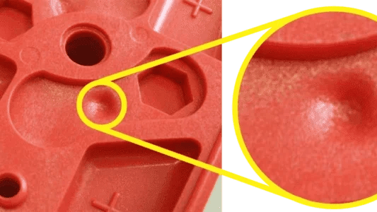 Close-up of a plastic part showing shrinkage marks and imperfections.
