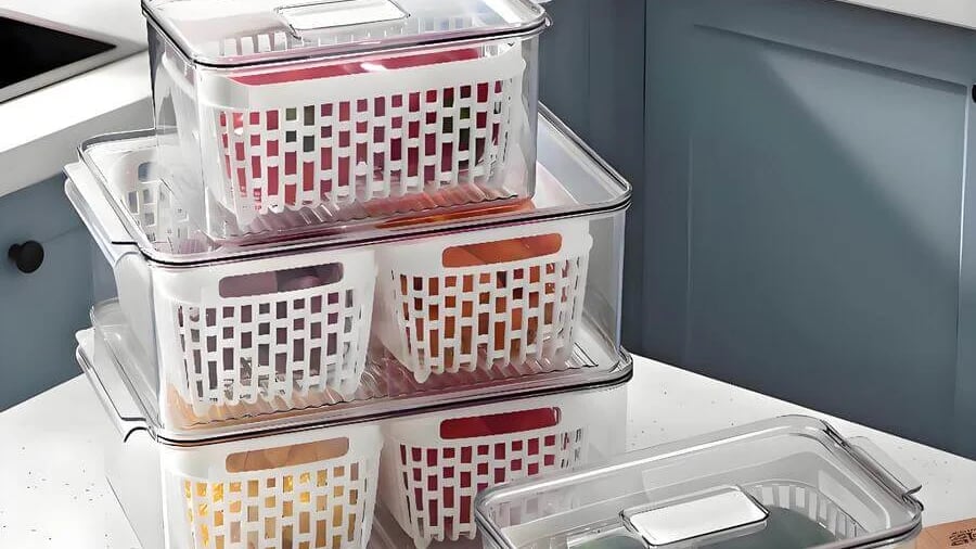 Stack of transparent storage containers with colorful baskets on a kitchen countertop