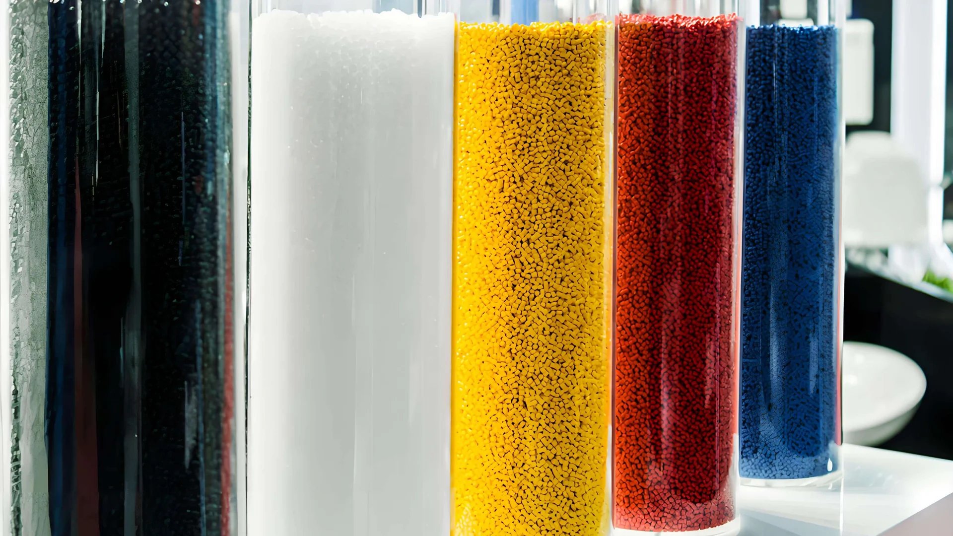 Transparent cylindrical containers filled with black, white, yellow, red, and blue granules