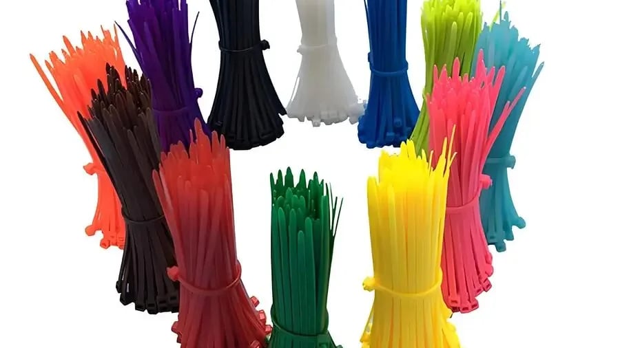 Freshly molded nylon cable ties cooling on a conveyor belt in a factory setting.