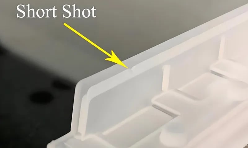 Close-up of a plastic part with a short shot defect indicated by an arrow